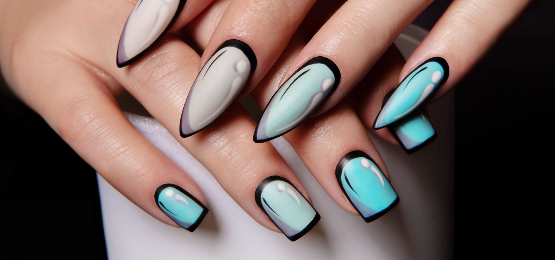 Manicura con una mano que tiene las uñas a pico y otra mano que en cuadrado.