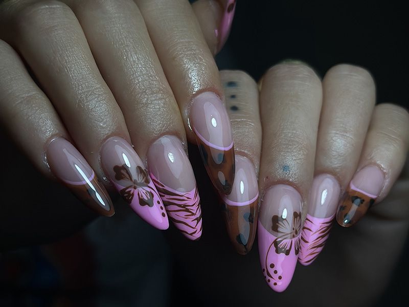 Uñas acrílicas en tonos rosas y marrones con diferentes dibujos.